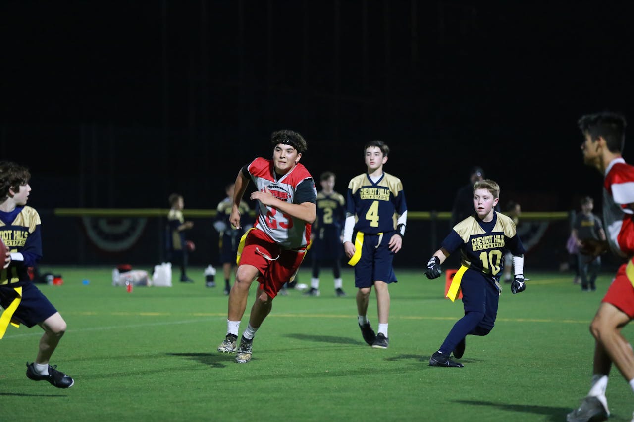A dynamic youth flag football game under lights in Los Angeles. Players in action on the field.